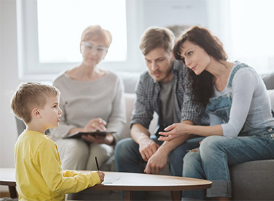 husband, wife, and therapist watching a child play