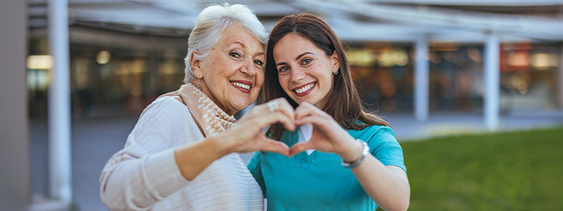 Woman and nurse making a heart with their hands