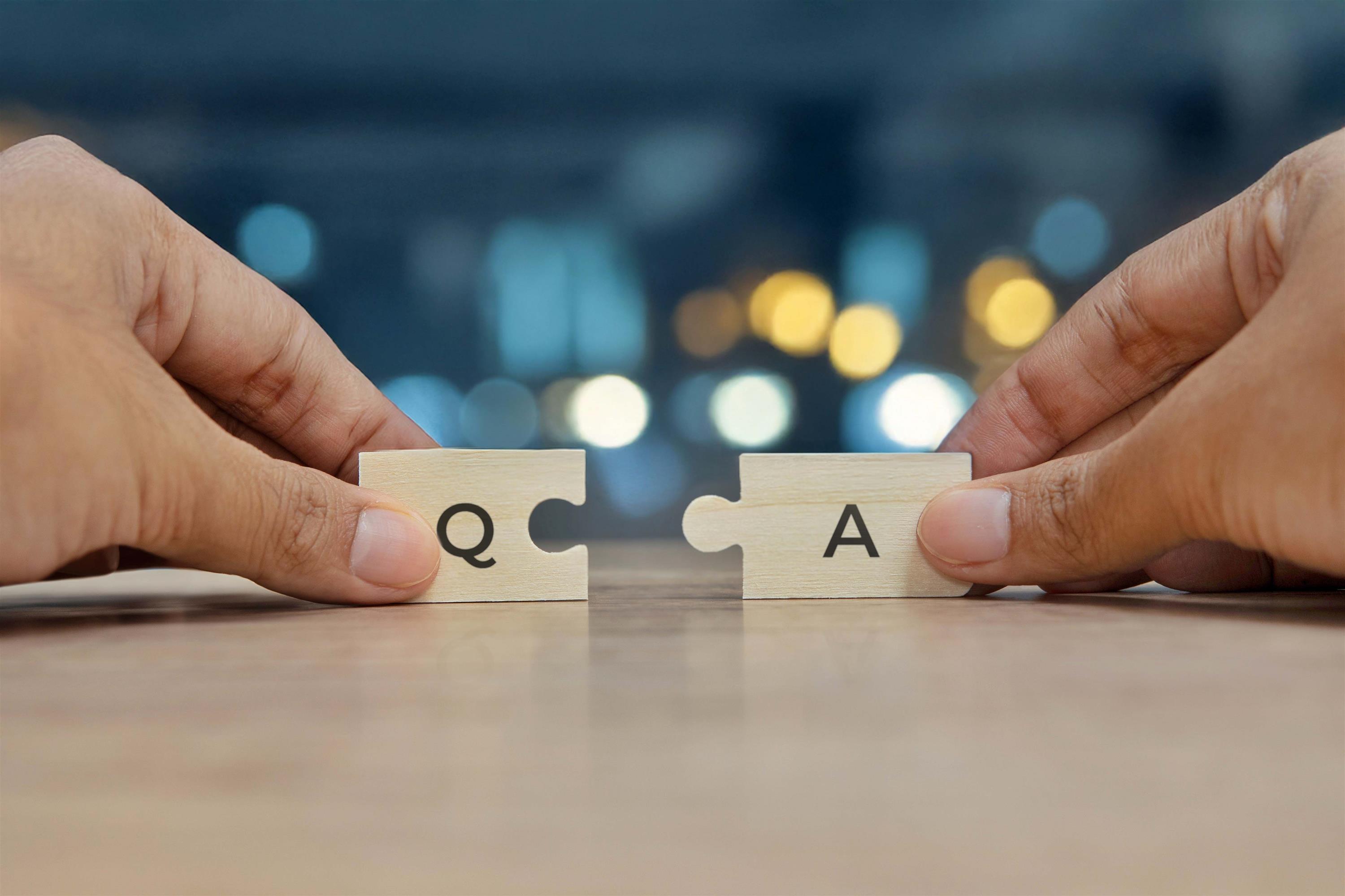 Person holding puzzle pieces that have the letters "Q" and "A"