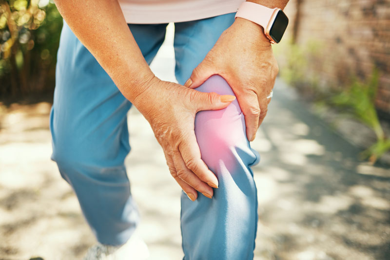 Woman-holding-knee-outdoors